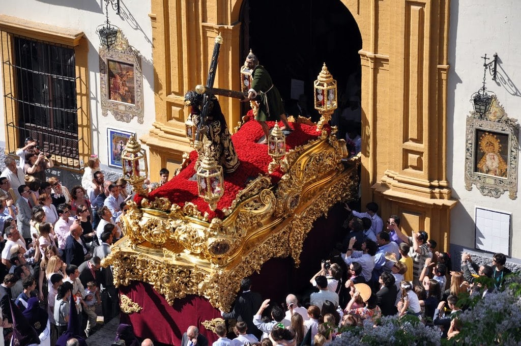 Es una fotografía de la salida desde la iglesia de una procesión de semana santa en Sevilla.